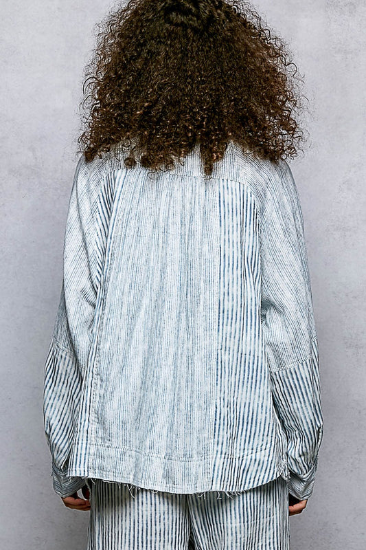 Person wearing a light blue striped shirt and pants against a gray background