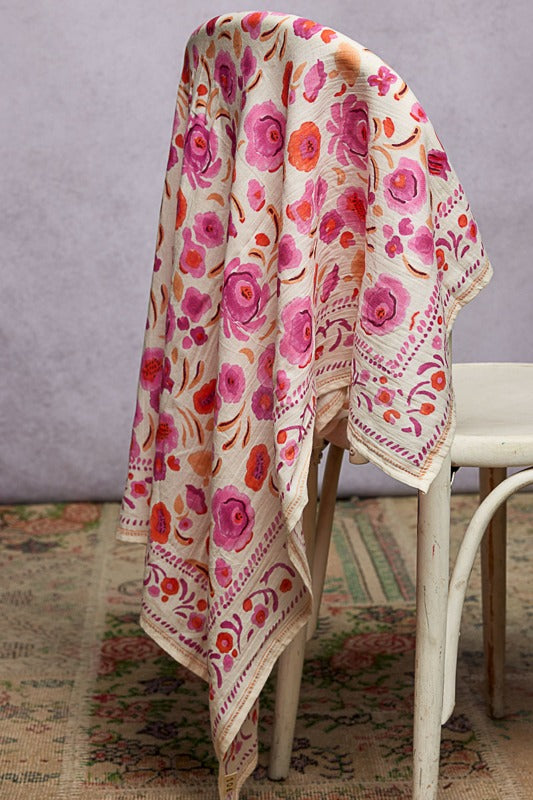 Floral patterned blanket draped over a chair against a neutral background