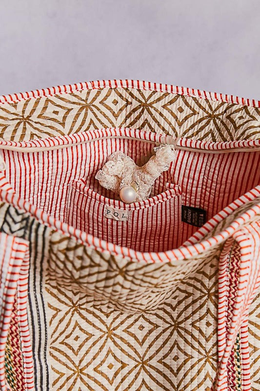 Close-up of a garment with geometric pattern and pearl brooch on a light gray background