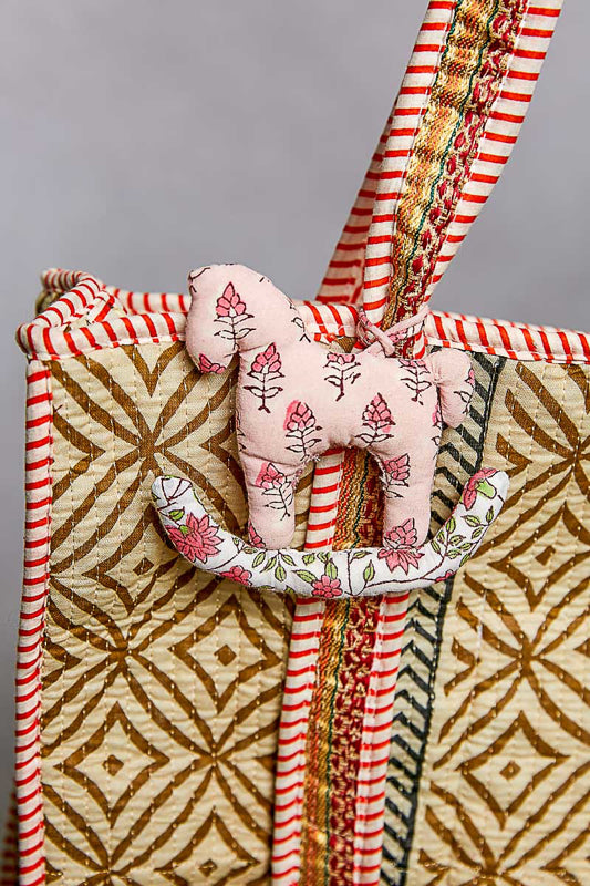 Decorative fabric horse shaped bag charm with a small pink fabric animal on a patterned fabric background