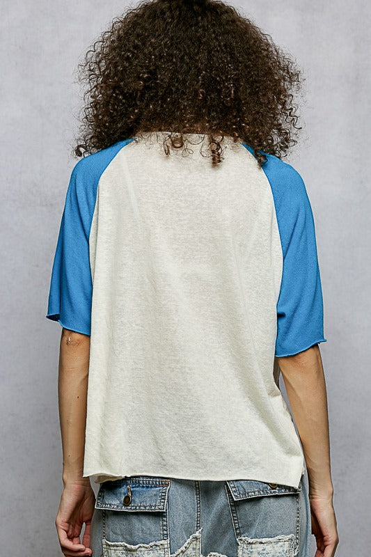 Person wearing a blue and white baseball shirt with a gray background