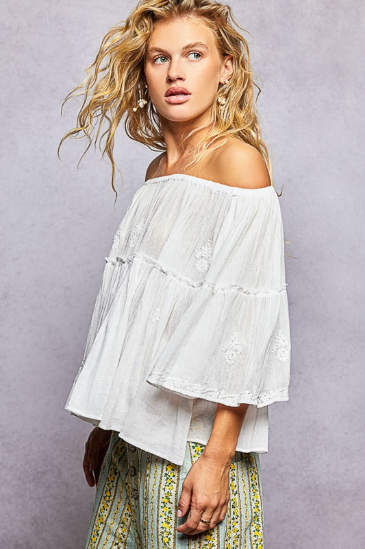 Woman wearing a white off-shoulder top with a gray background