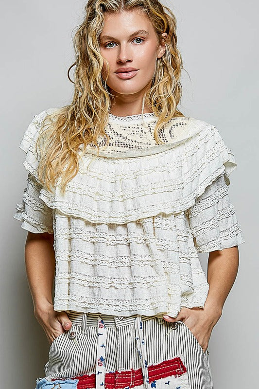 Woman wearing a layered lace top with a plain background