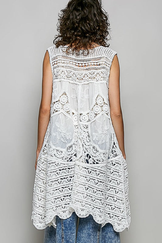 Woman wearing a white lace dress against a gray background