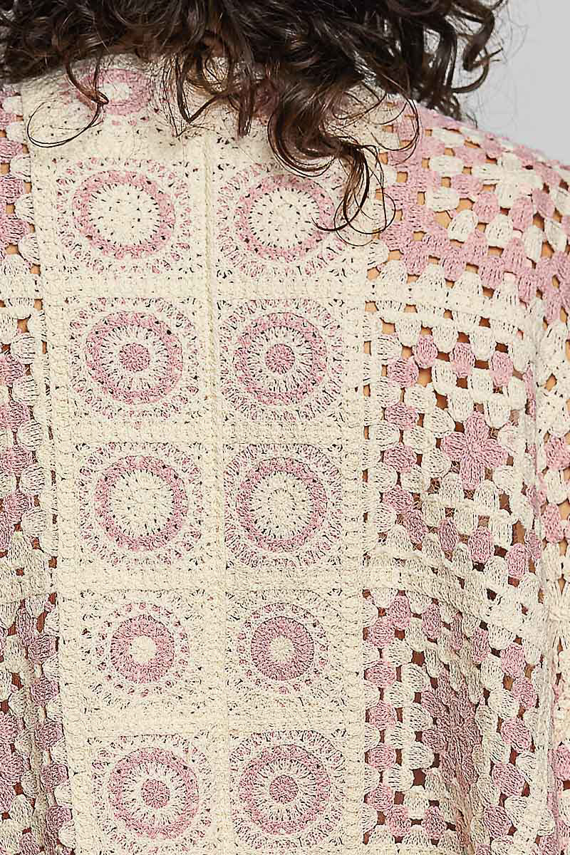 Close-up of a crocheted garment with a pink and white pattern.