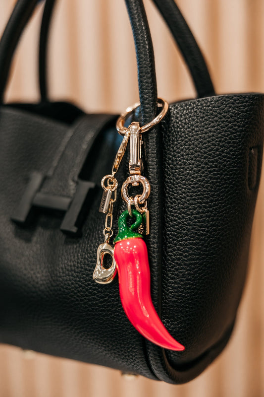 Black handbag with a red chili pepper keychain attached