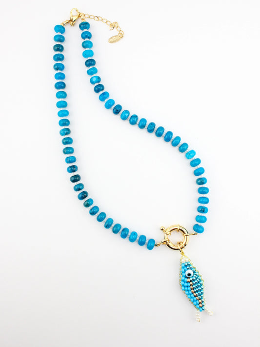 Turquoise beaded necklace with a gold and blue pendant on a white background