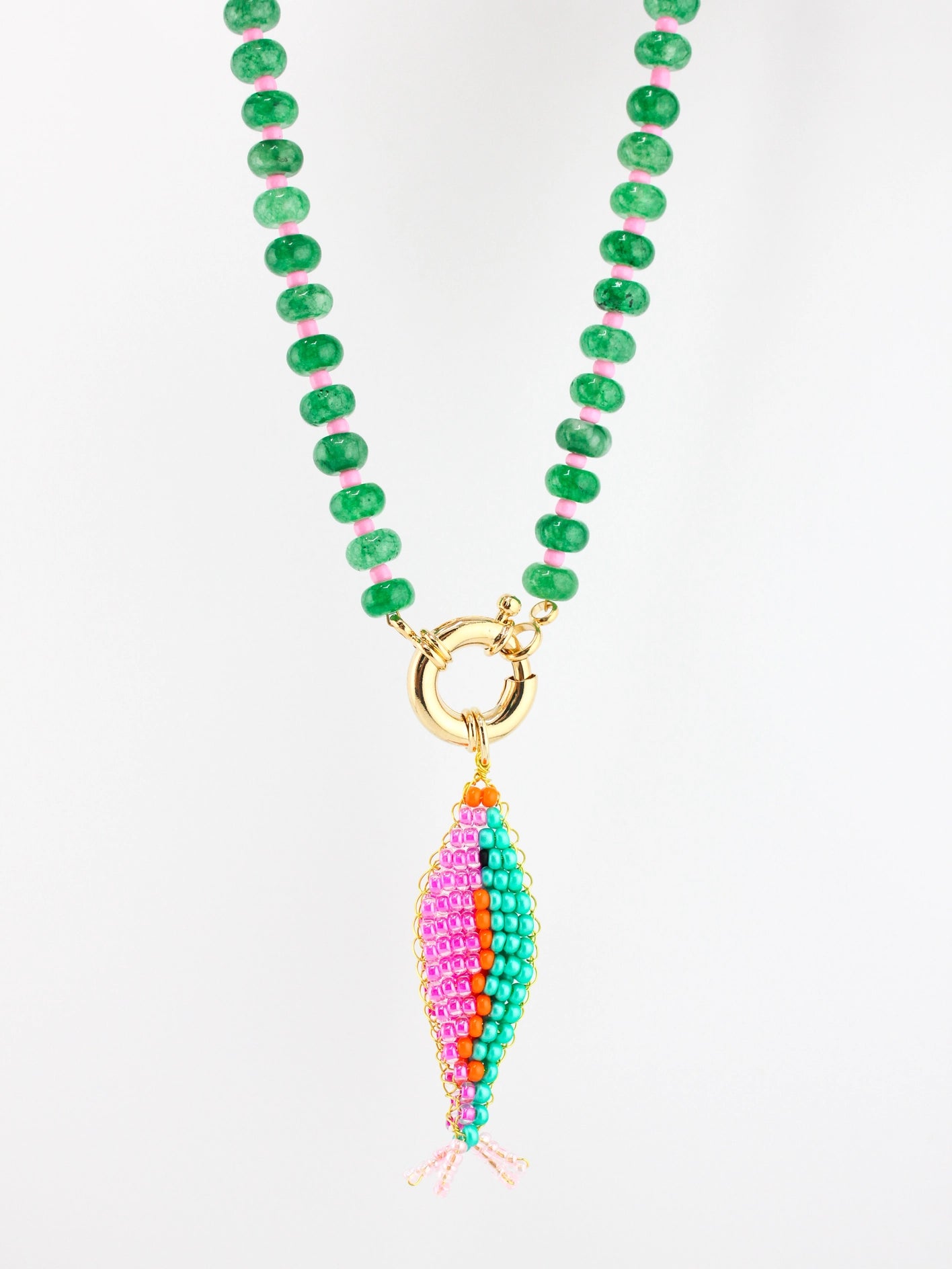 Necklace with green beads and a colorful fish-shaped pendant on a white background