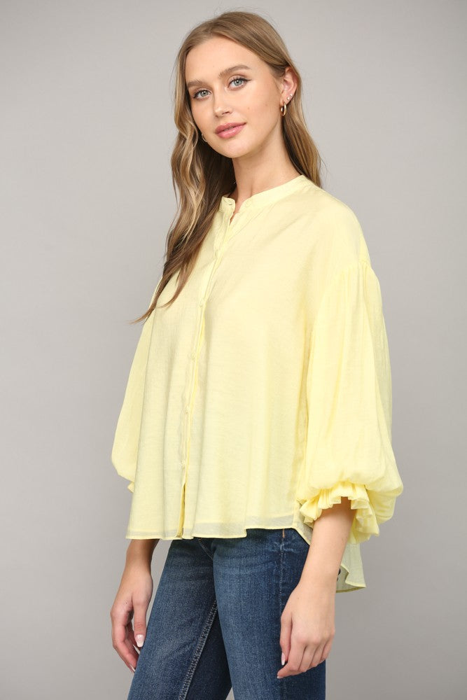 Women wearing a yellow blouse with blue jeans on a grey background.