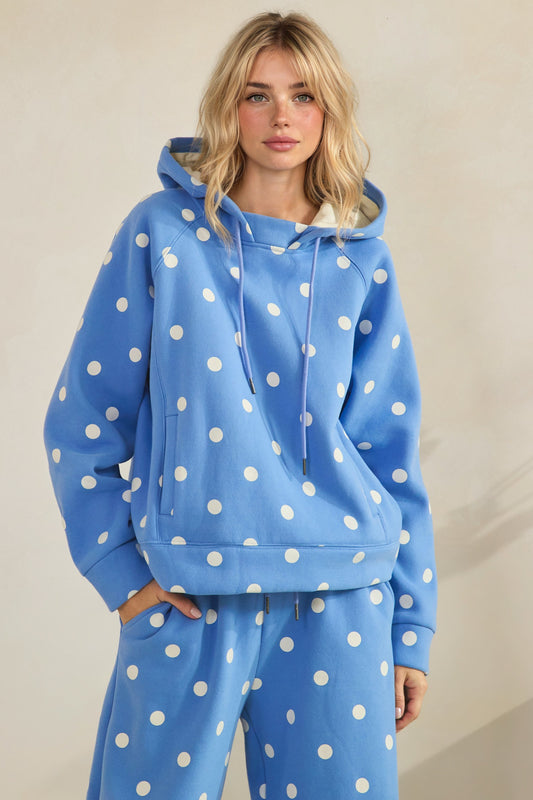 Person wearing a blue hoodie with white polka dots on a plain background