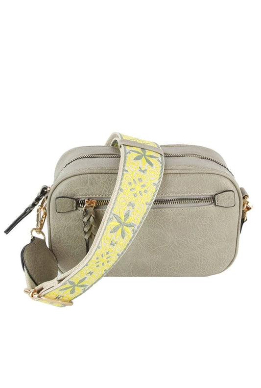 A grey bag with a boho guitar strap on a white background.