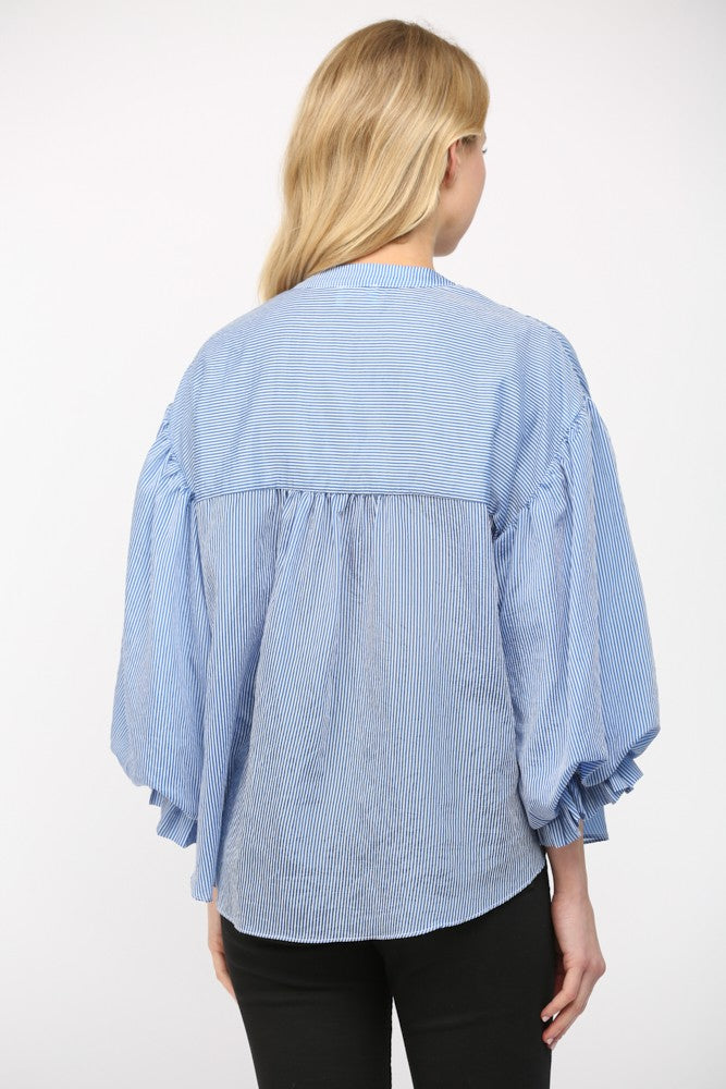Women wearing a blue stripe blouse with black jeans on a white background.