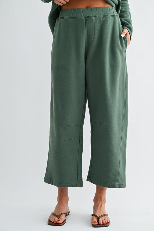 Green wide-leg pants worn by a person on a white background