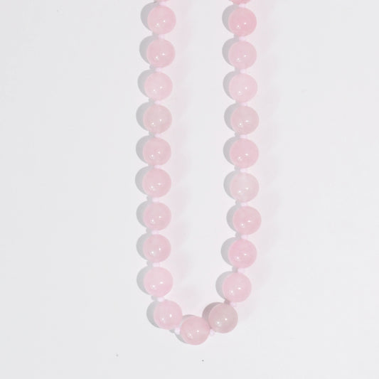 A pink beaded necklace on a white background.