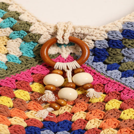 Colorful crocheted blanket with a wooden ring and beads on top
