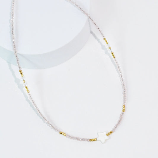 A light pink beaded necklace with a star pendant.