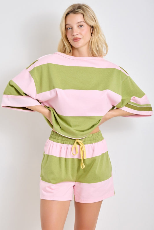 Woman wearing a pink and green striped outfit against a white background