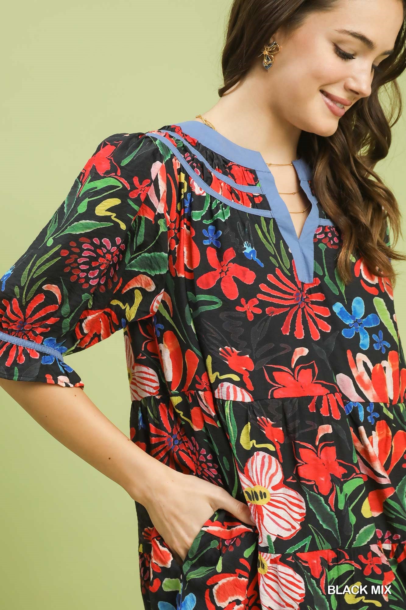 Woman wearing a colorful floral dress against a light green background
