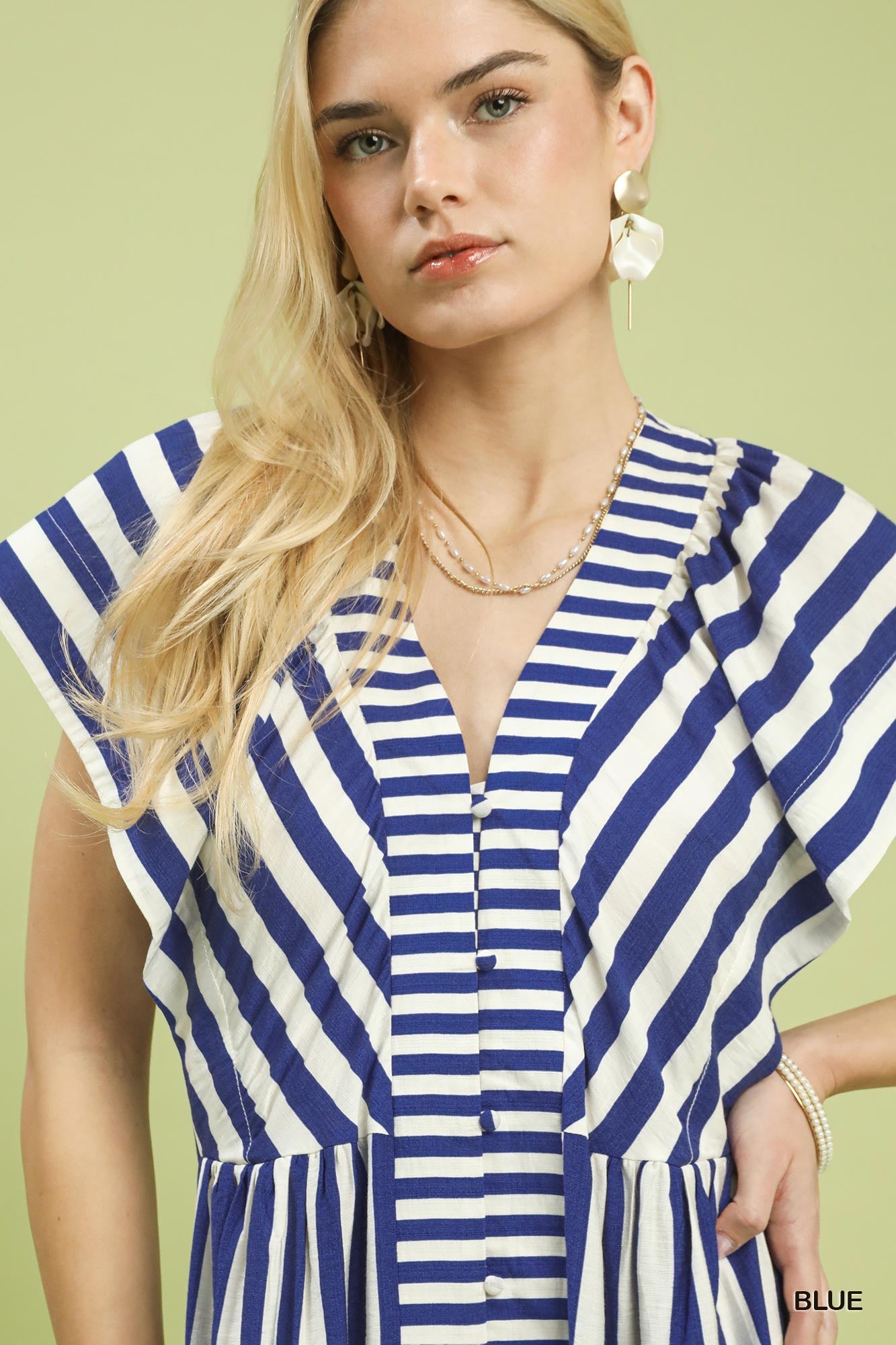Woman wearing a blue and white striped dress against a light green background