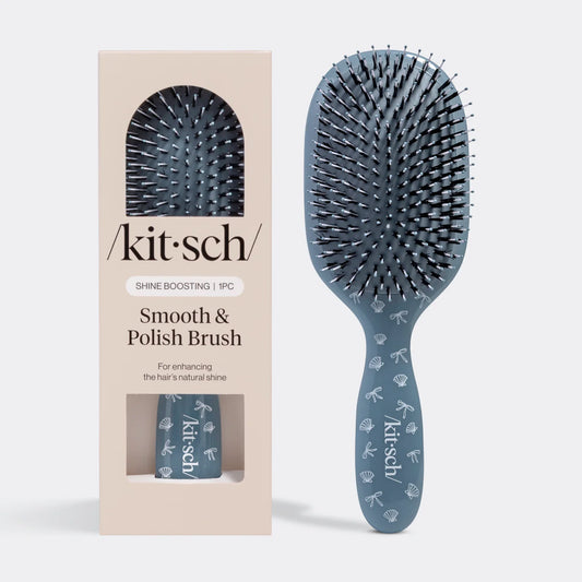 Blue hairbrush with packaging labeled 'kitsch' on a white background