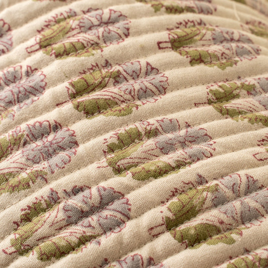 Close-up of a quilt with green and red floral patterns on a beige background