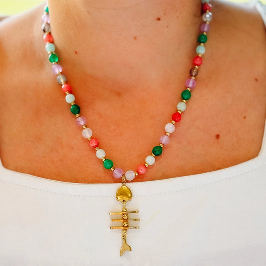 women wearing a beaded necklace with a fishbone gold prendant .