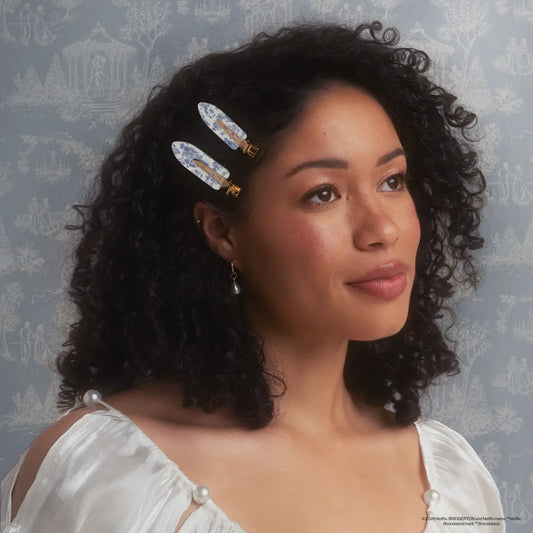 Woman with decorative hair pins in her curly hair against a patterned wall.