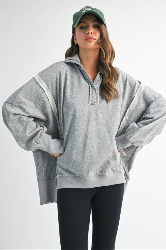 Woman wearing a gray oversized hoodie and black leggings on a white background