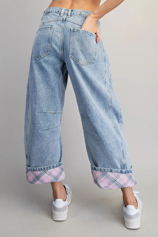 Light blue jeans with plaid cuffs worn by a person on a gray background