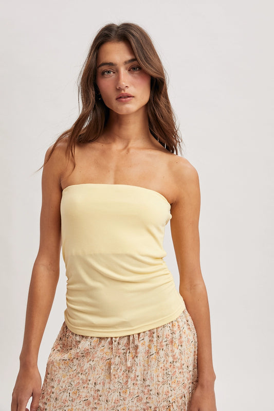 Women wearing a yellow tube top on a plain background.
