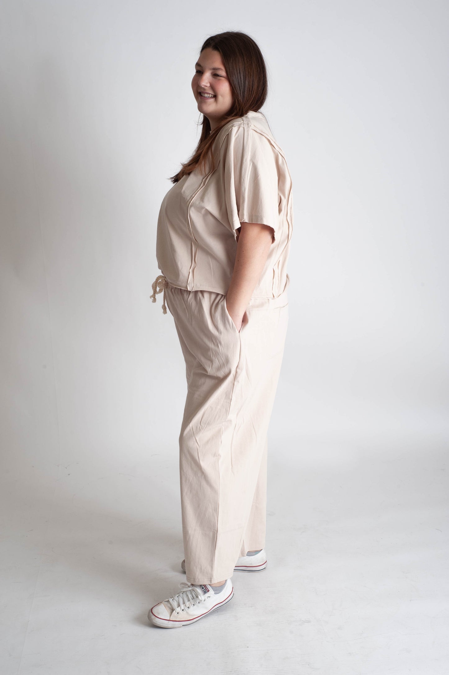Woman wearing a beige outfit with a matching top and pants on a white background