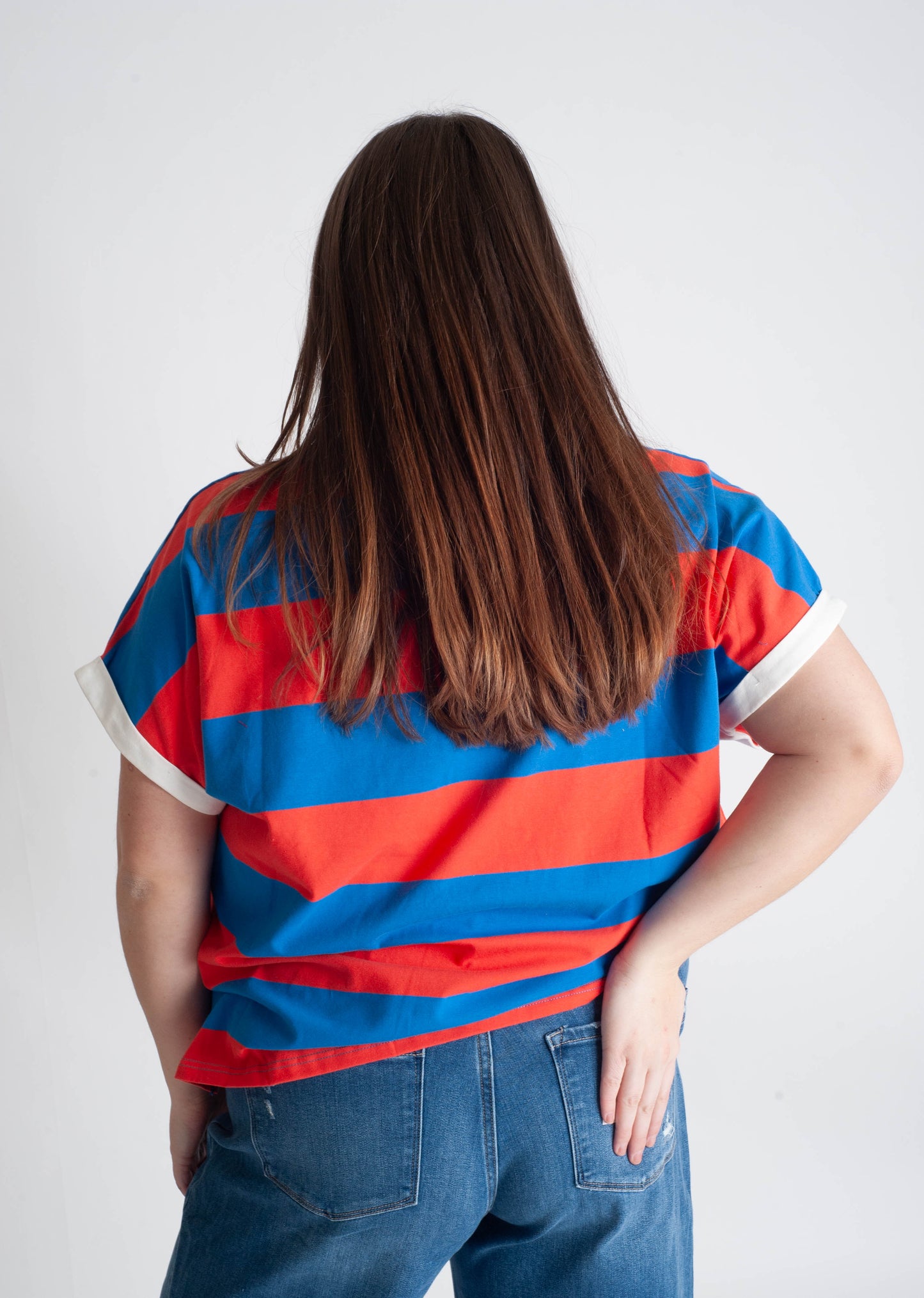 Person wearing a red and blue striped shirt with a plain background