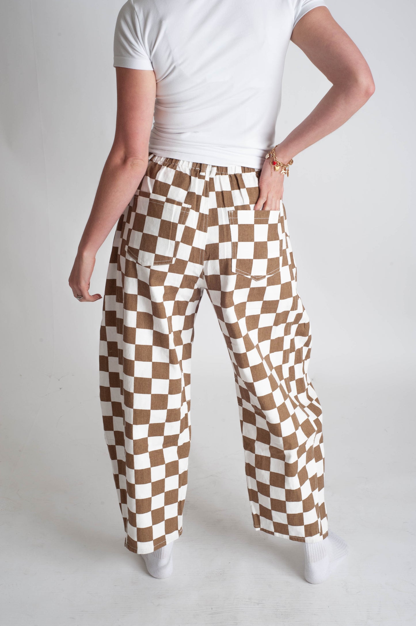Person wearing brown and white checkered pants on a plain background