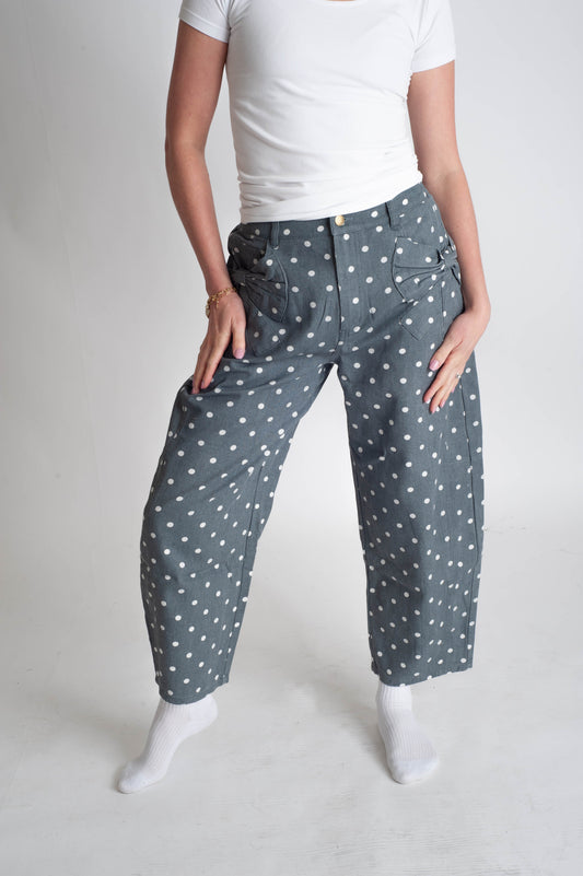 Person wearing blue pants with white polka dots on a plain background