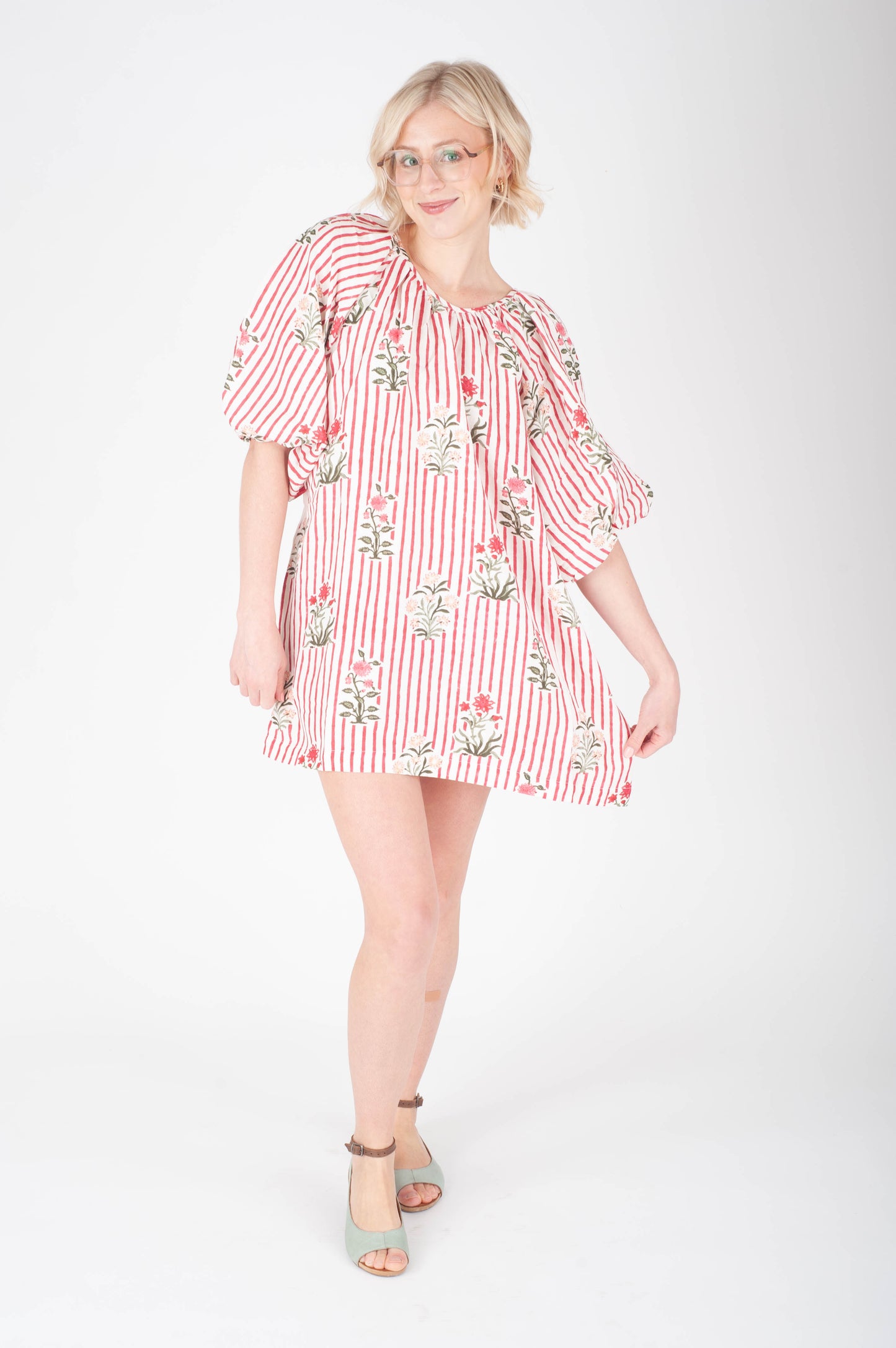 Woman wearing a red and white striped dress with floral patterns on a white background