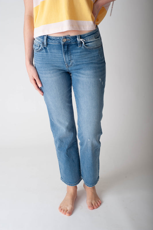 Person wearing blue jeans and a yellow top on a plain background