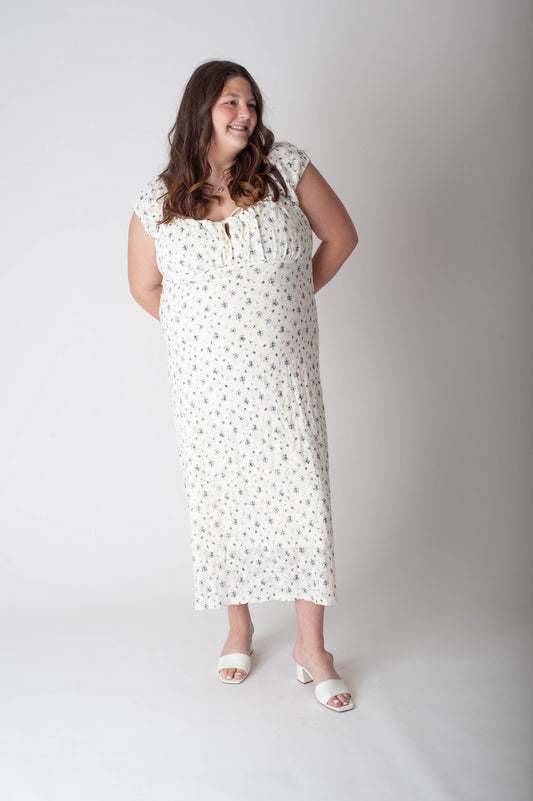 Woman wearing a white dress with black polka dots against a plain background