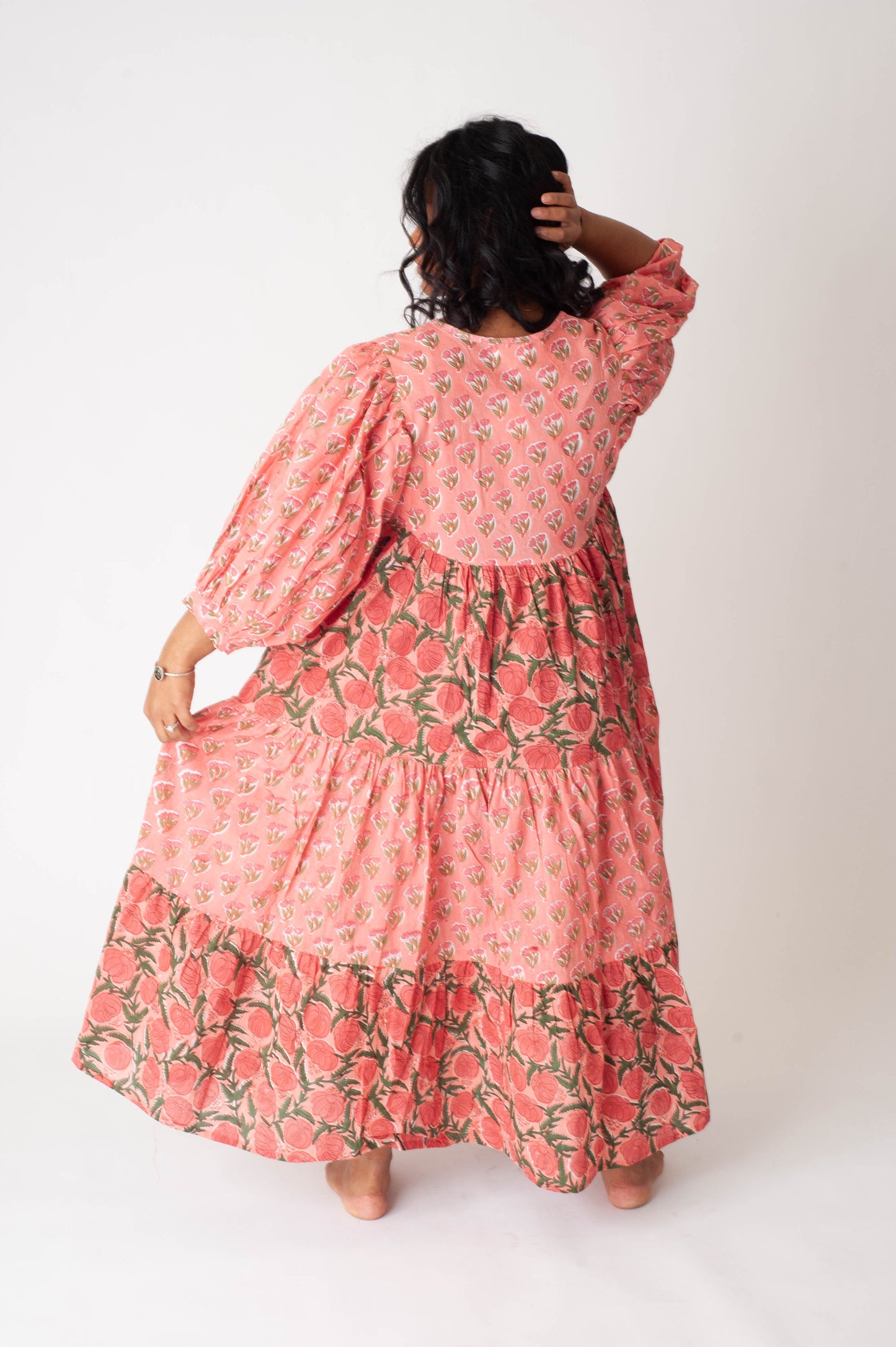Person wearing a pink floral dress against a white background