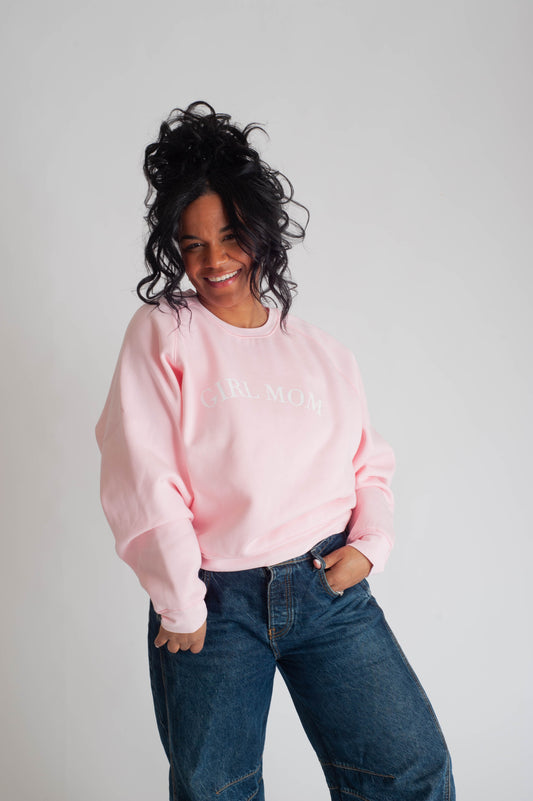 Person wearing a pink sweatshirt with text and blue jeans on a plain background
