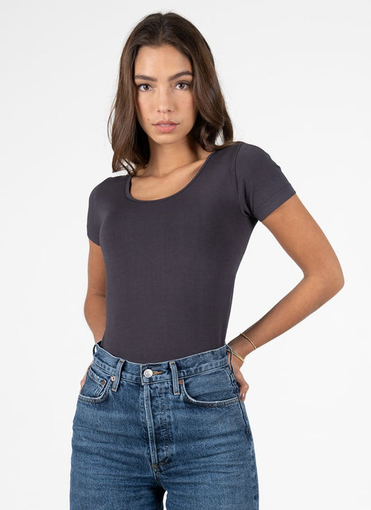 A woman wearing a short sleeve scoop neck top in grey with jeans.