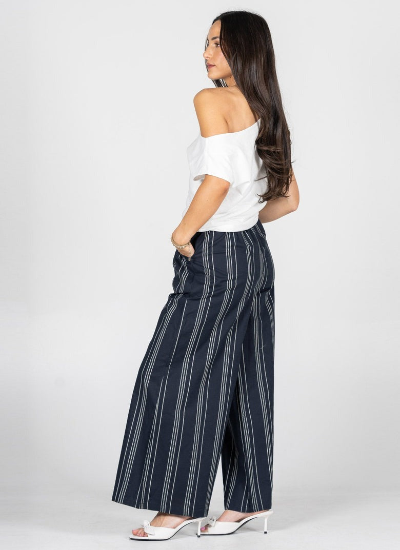 Woman wearing navy striped pants and a white top on a white background