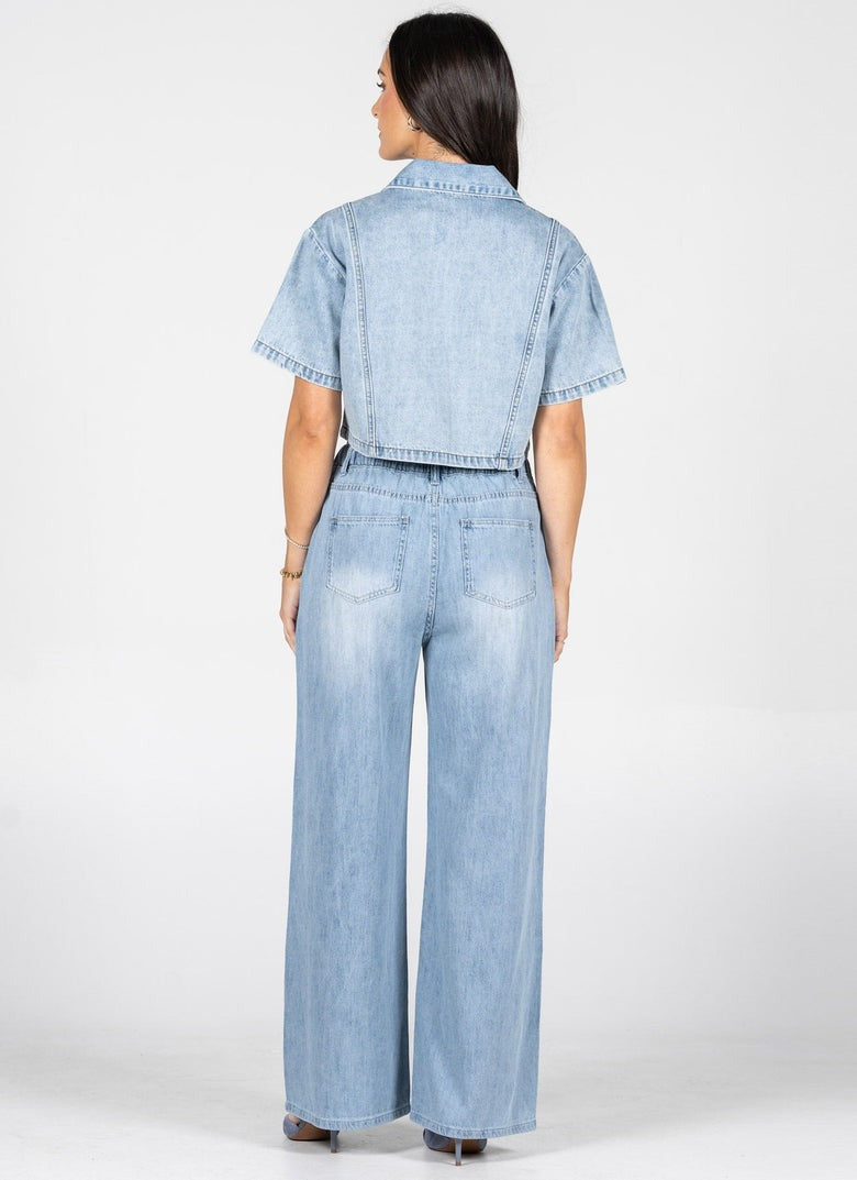 Person wearing a light blue denim outfit on a white background