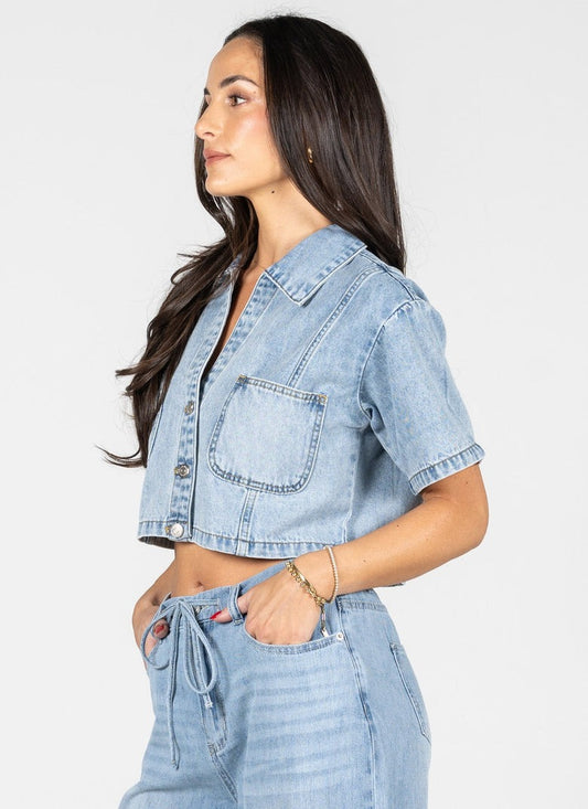 Woman wearing a light blue denim jacket and pants on a white background