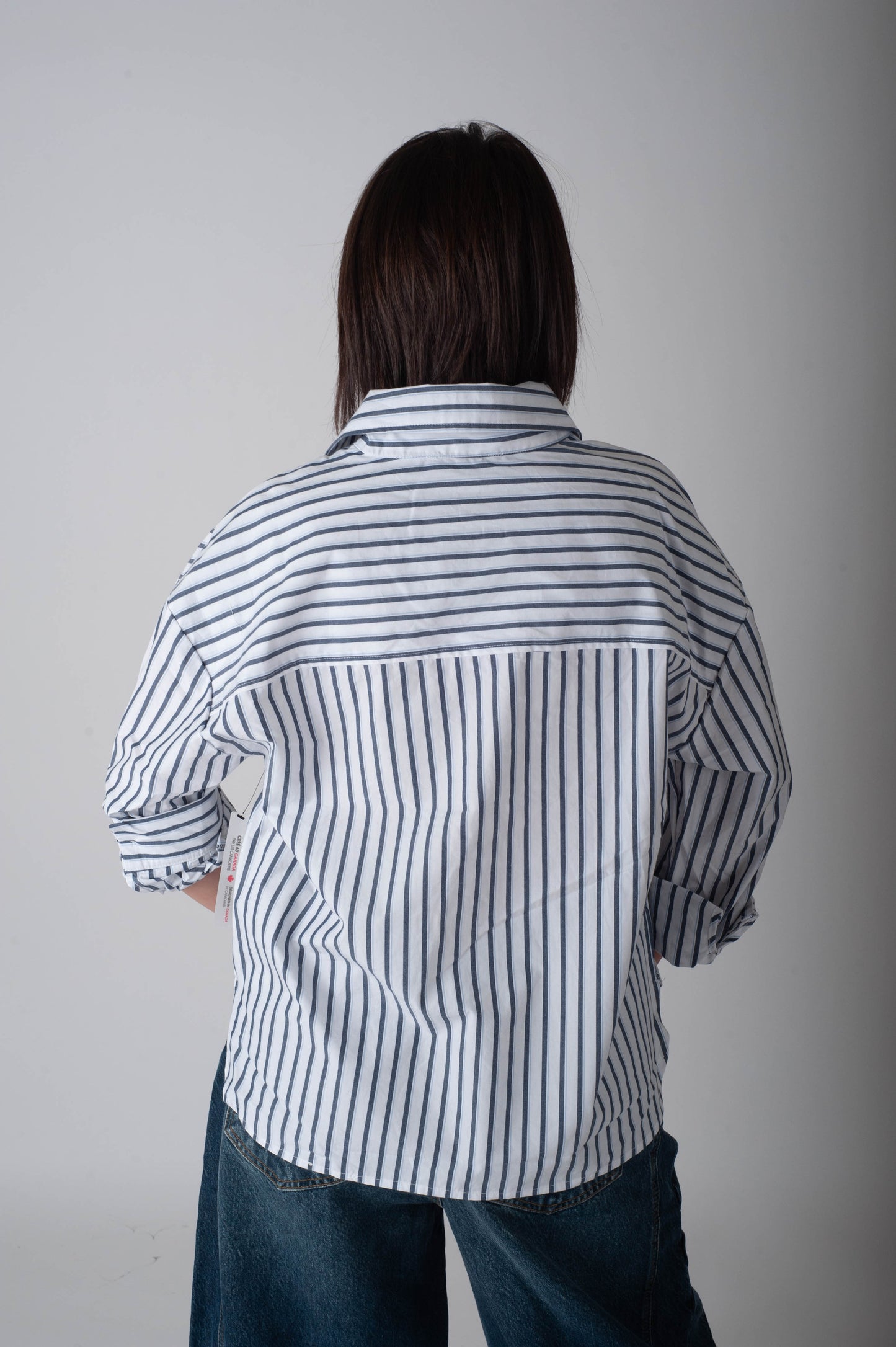 Person wearing a striped shirt and jeans against a plain background