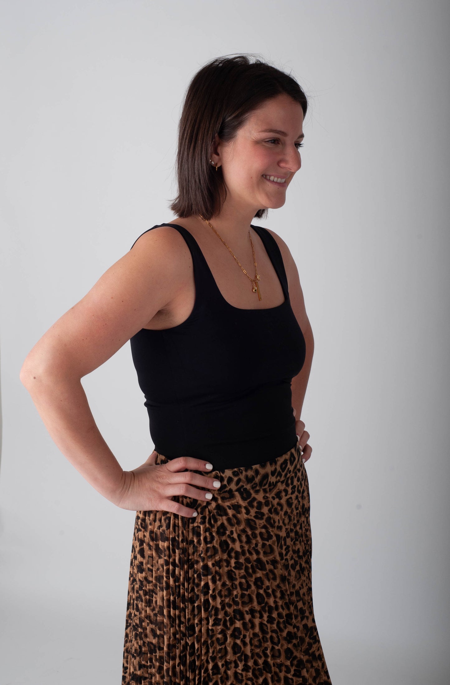 Woman wearing a black tank top and leopard print skirt against a plain background