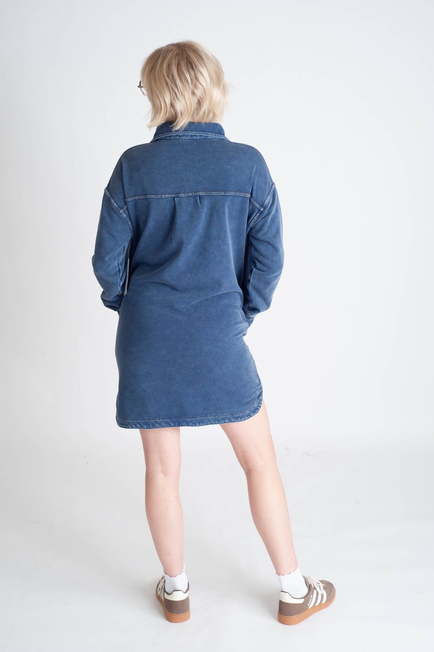 Person wearing a blue denim dress on a white background