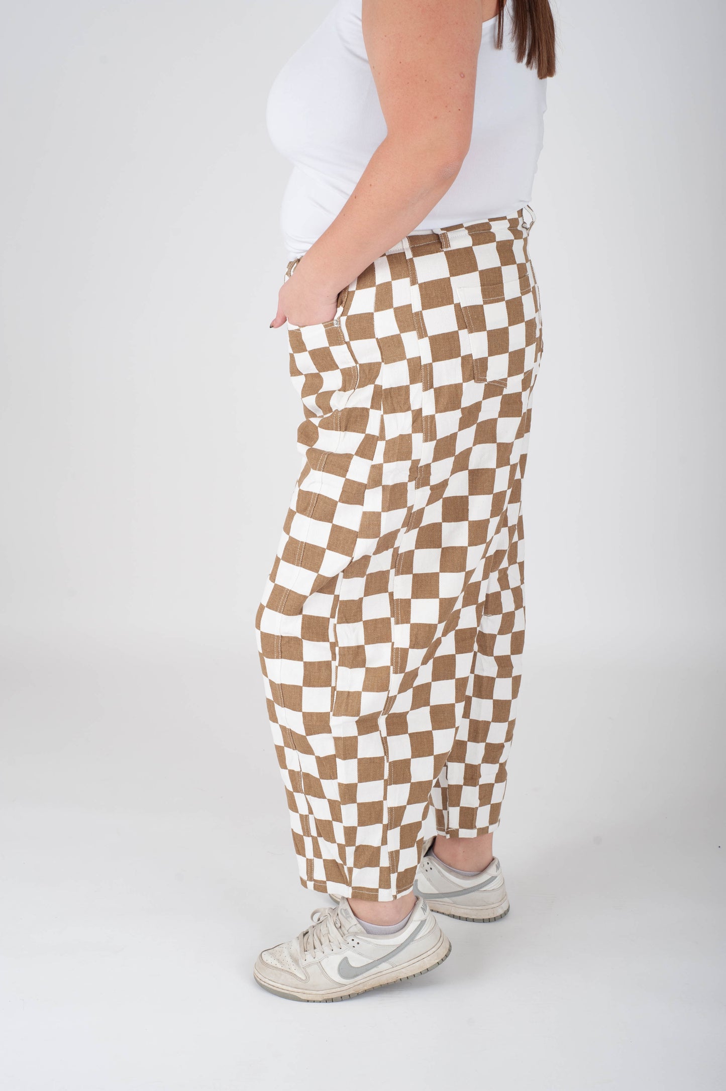Person wearing brown and white checkered pants on a white background