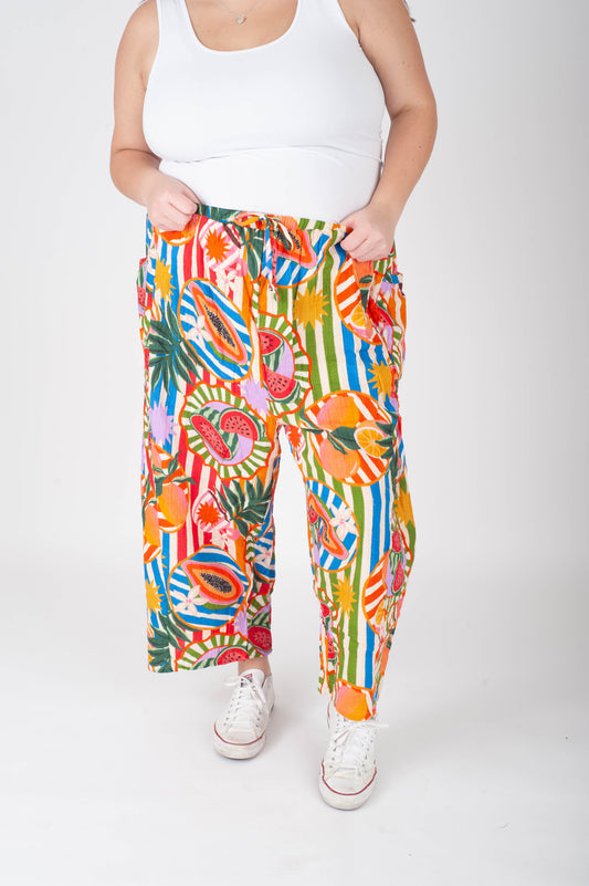 Person wearing colorful tropical print pants and white sneakers on a white background