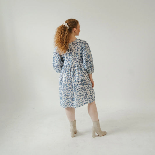 Woman wearing a blue floral dress standing against a white background