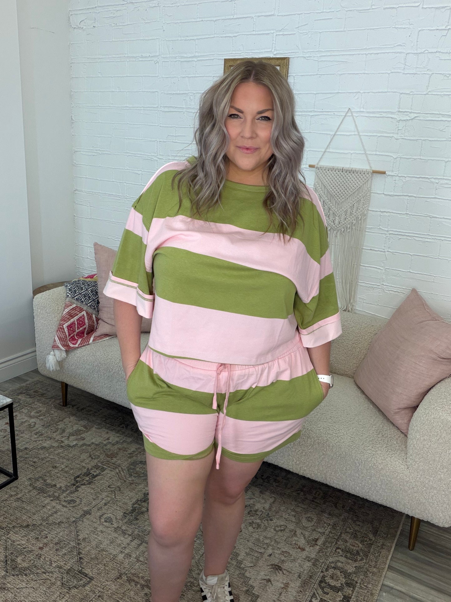 Woman wearing a green and pink striped outfit standing in a living room.